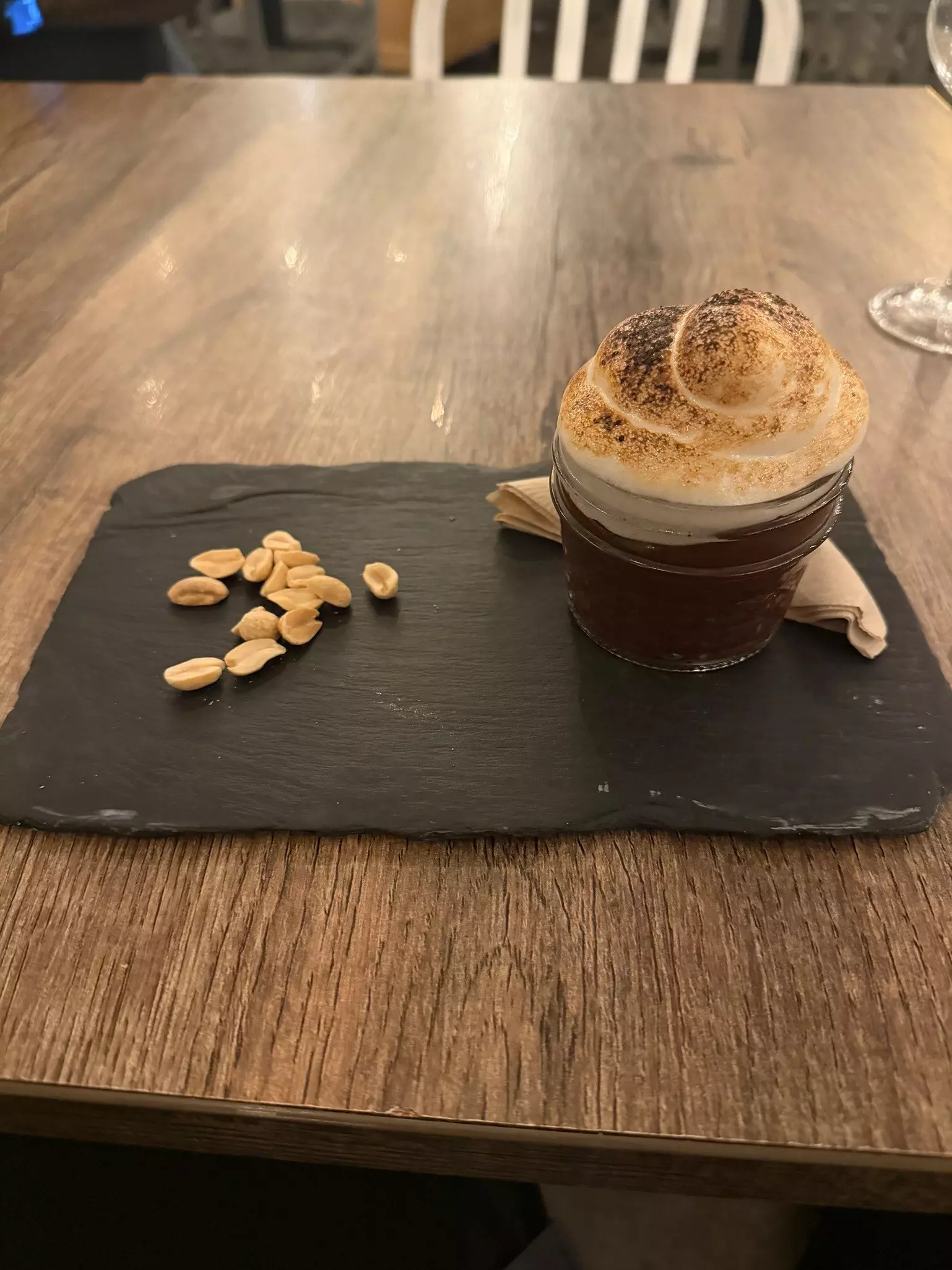 Closeup of a peanut parfait which includes chocolate mousse, peanut butter mousse, marshmallow fluff and toasted peanuts on a black tray.