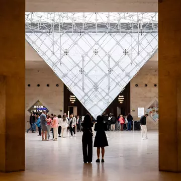 People standing in front of the Inverted Pyramid (Pyramide Inversée) located in the Carrousel du Louvre shopping mall in front of the Louvre Museum.