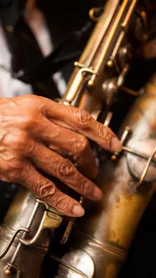 A saxophonist's hands on the keys of a saxophone.