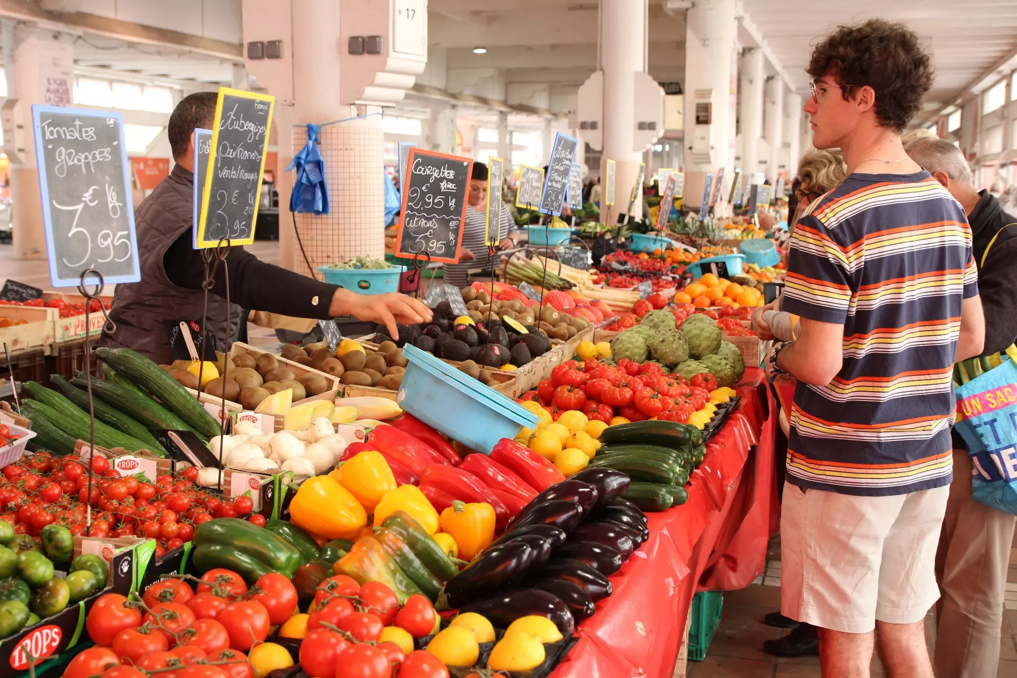 A male customer shops for peppers, zucchini, artichokes and other fresh produce at an indoor market.