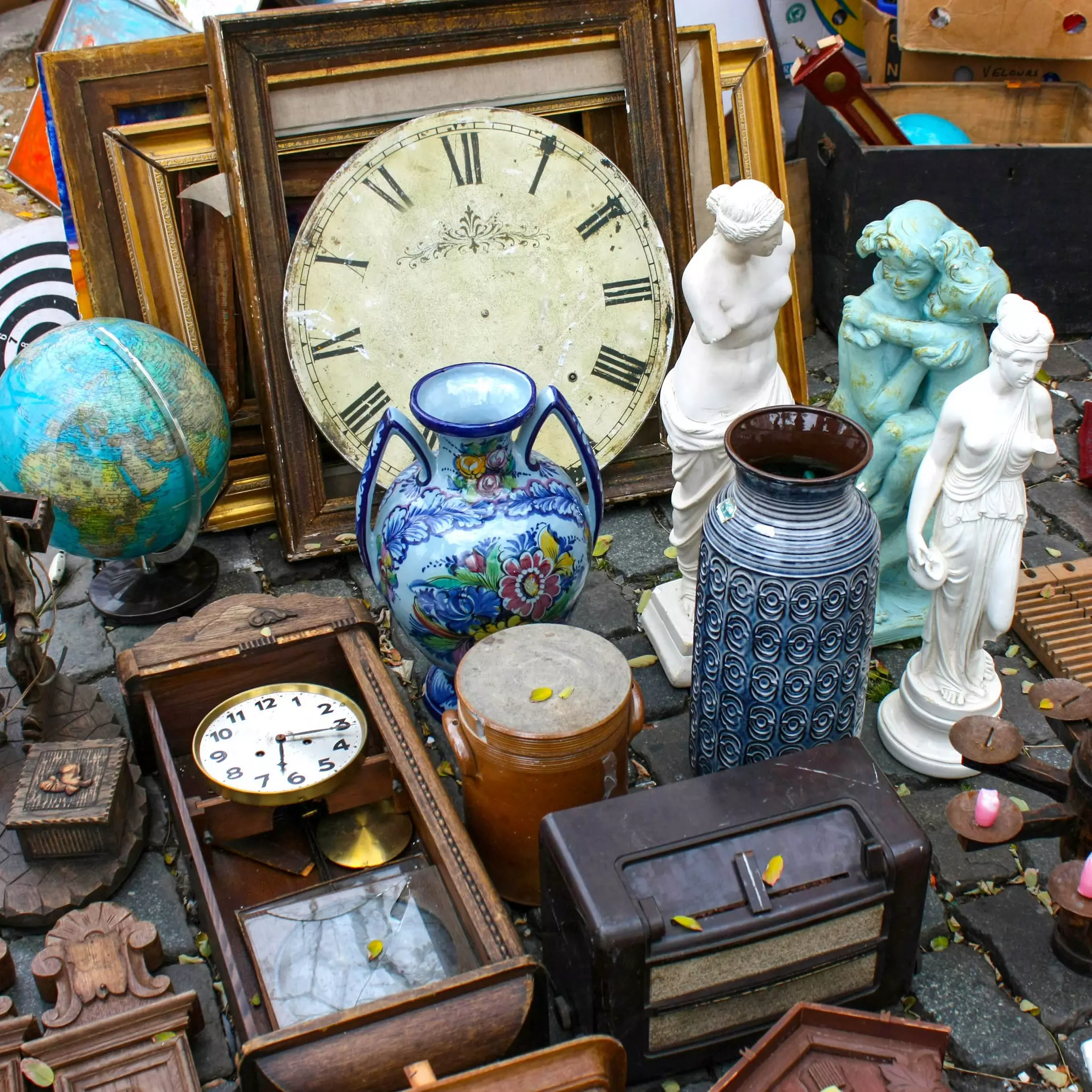 Various antique objects including a clock and vase at a flea market stand at the Braderie de Lille - France 