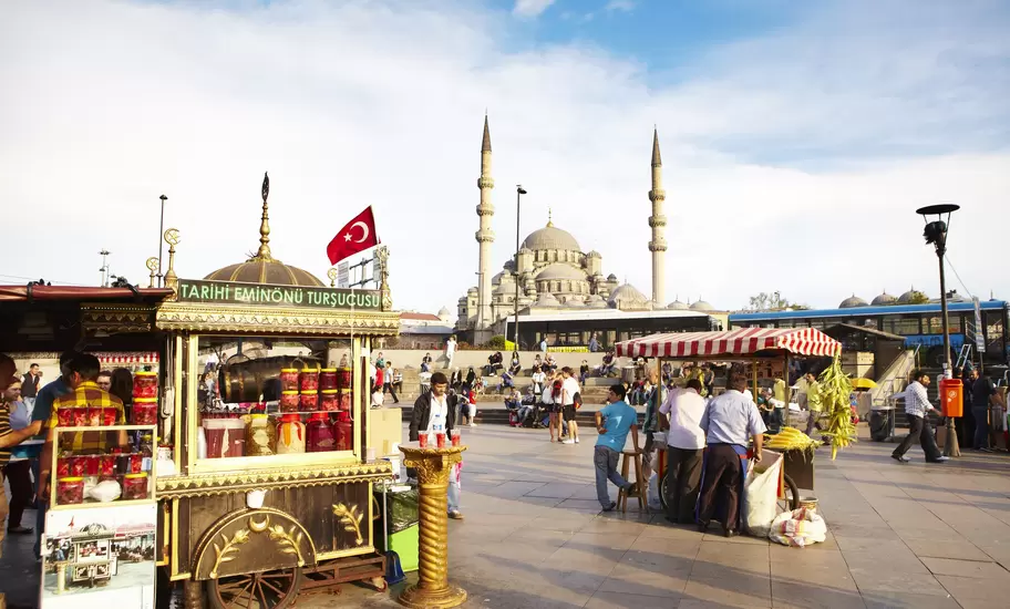 Ornate Tarihi Eminönü Turşucusu pickle cart and Turkish flag in Istanbul's Eminönü square, Yeni Cami mosque behind