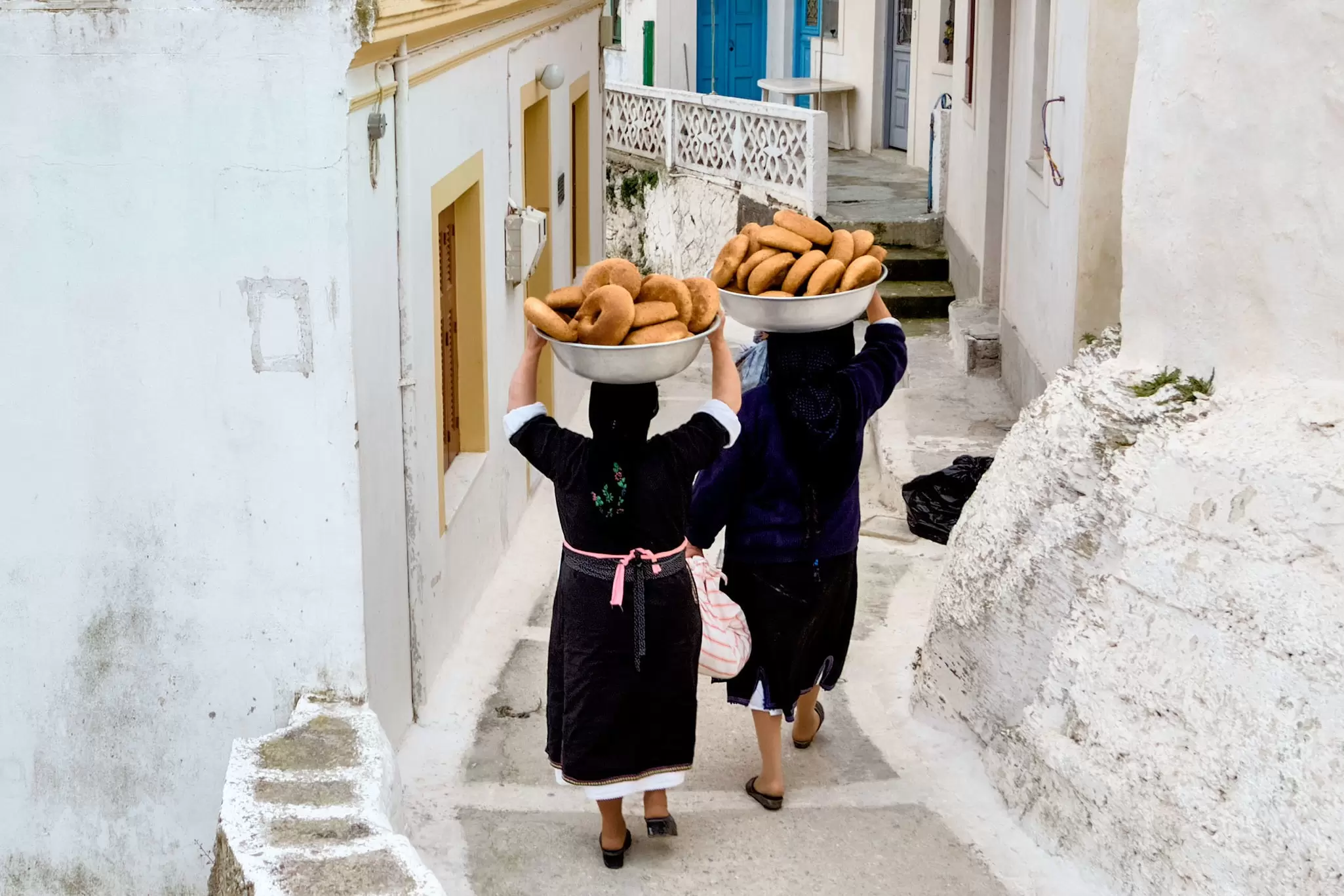 Women carry bowls of bread for Easter celebrations down a narrow lane in Olympos on Karpathos Island.