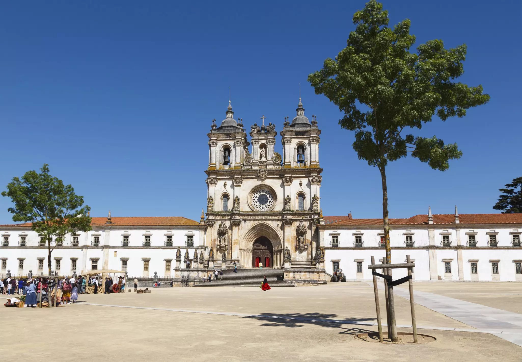 A vast monastery building with white walls, red tiled roofs and a central entrace with two bell towers.
