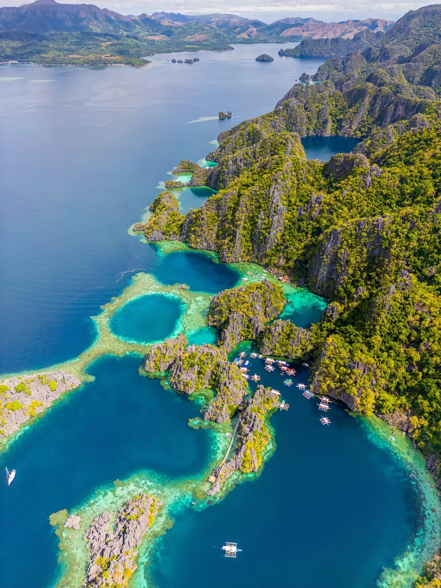 Aerial view of a blue lake and lagoons with boats in Palawan, Philippines
