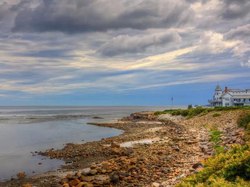 A hotel overlooks a quiet bay on a cloudy evening.