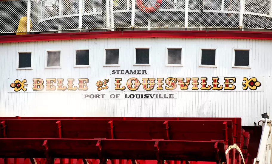 Belle of Louisville steamboat stern in Louisville, Kentucky, with red paddlewheel; sign reads Steamer Belle of Louisville