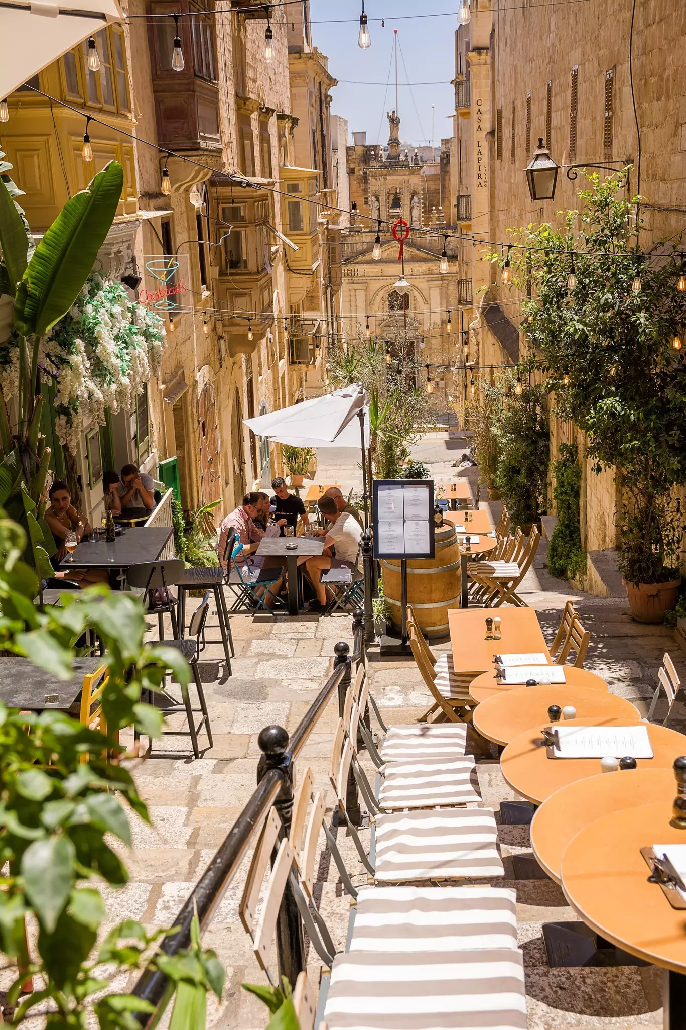 Staircase with building and umbrellas with cafe tables at restaurants in Valletta, Malta