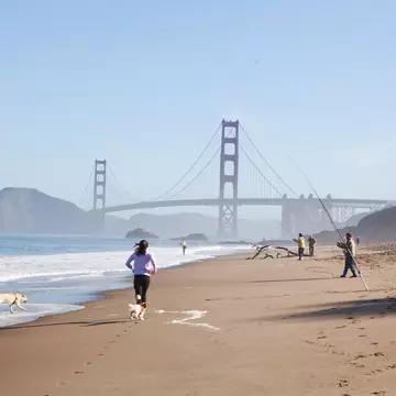  People running and fishing on baker beach close to Golden Gate bridge. Oleg Podzorov / Shutterstock