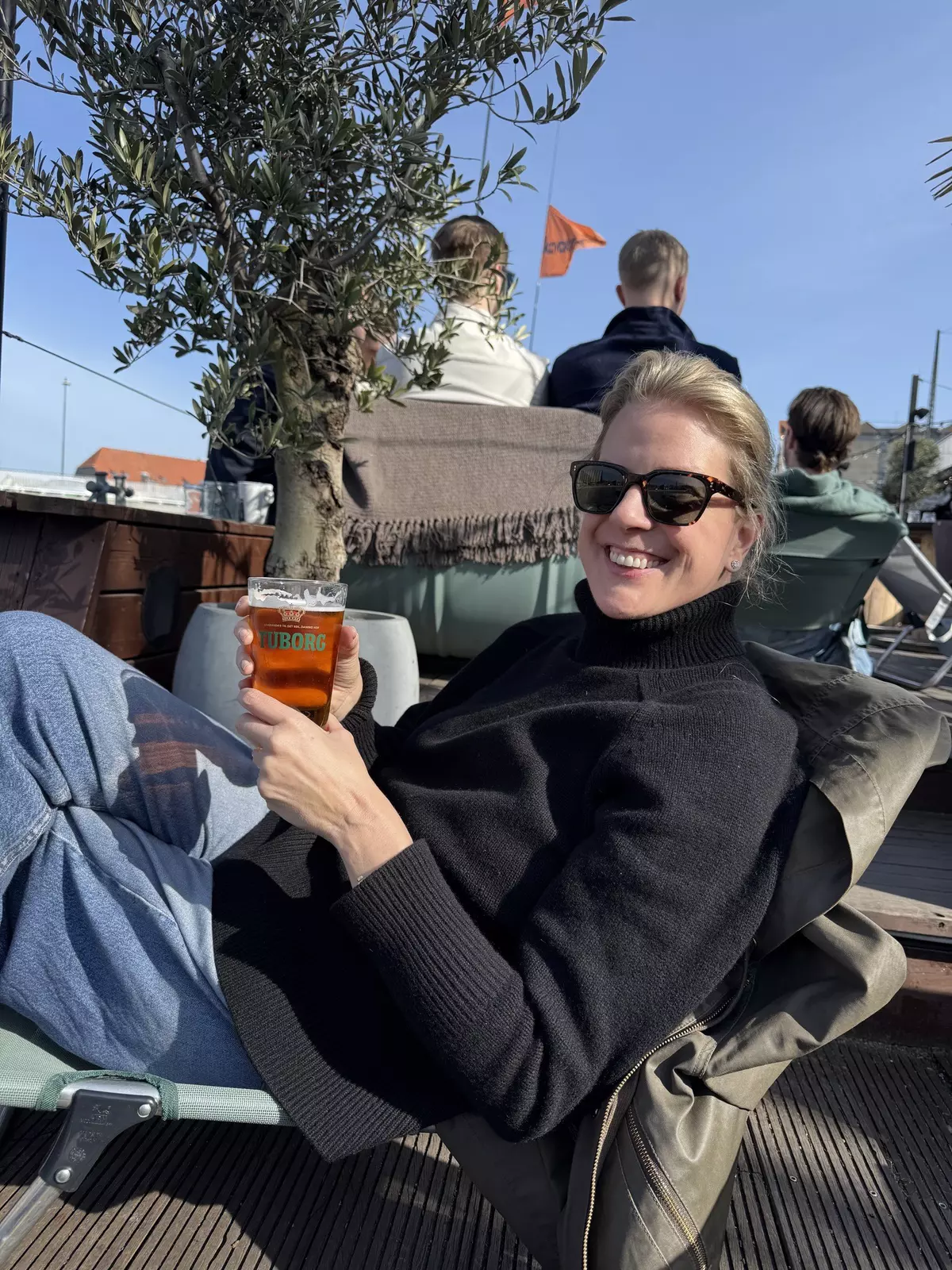 Close-up of woman sitting on a rooftop bar with a drink in hand.Brekke at Kayak Bar in Copenhagen