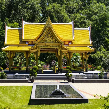 The golden, pagoda-life roof of the Thai Pavilion seen among ornamental plantings at Olbrich Botanical Gardens