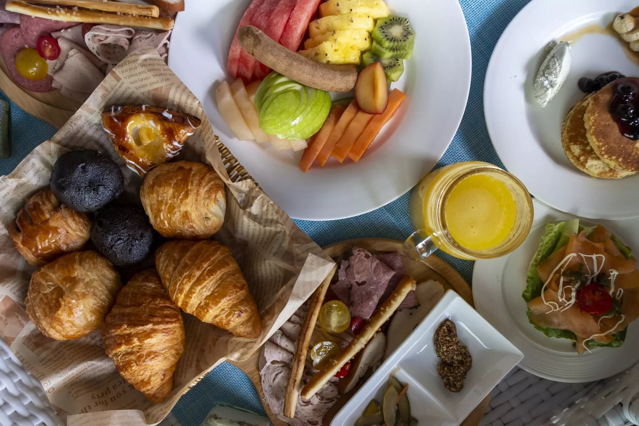An overhead view of croissants, pastries, fruit and other breakfast items.
