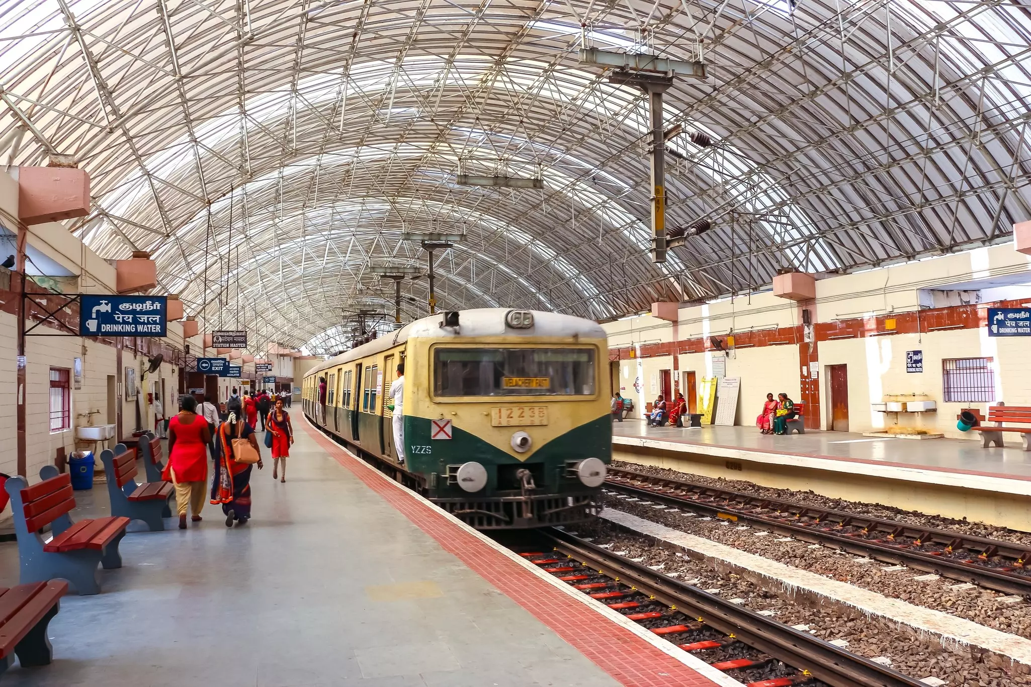 A train station with people boarding a small train that serves local routes.