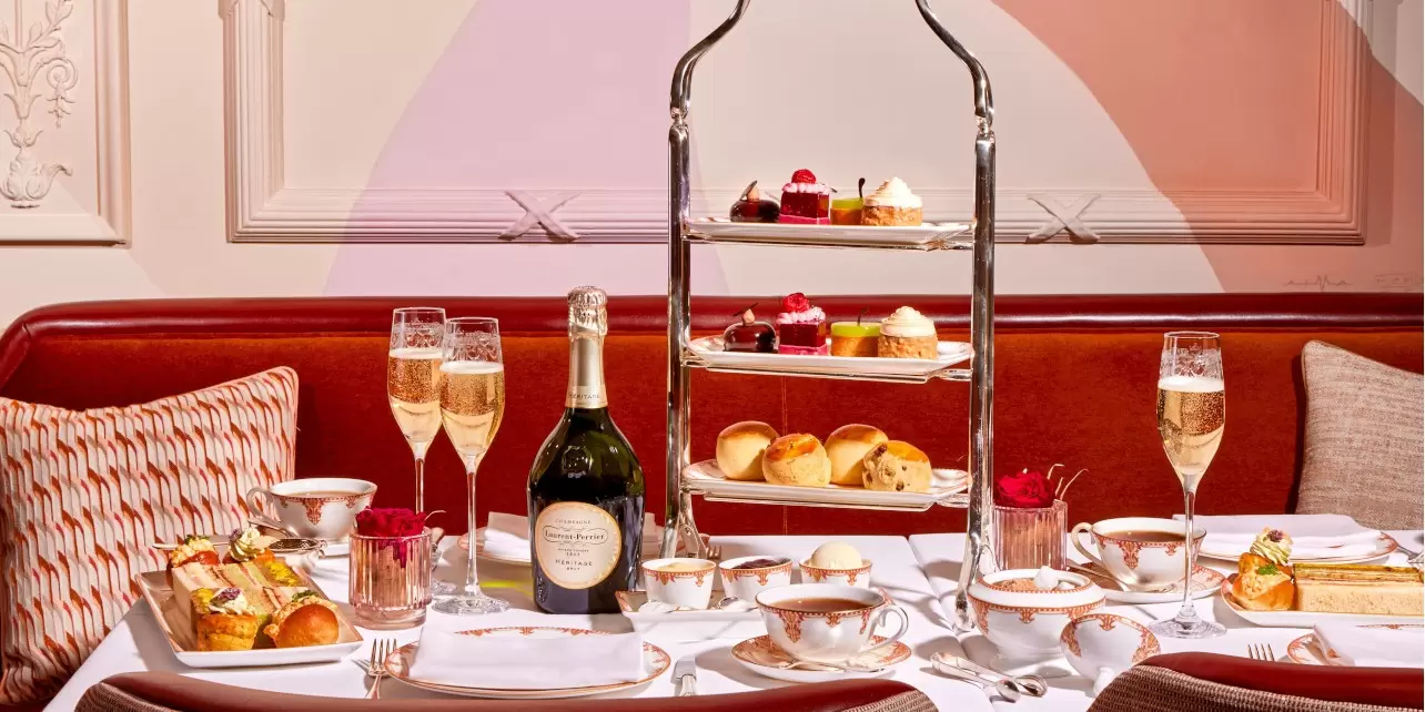 Luxurious table laid with champagne bottle and glasses and afternoon tea, cakes, tea at The Savoy in London 