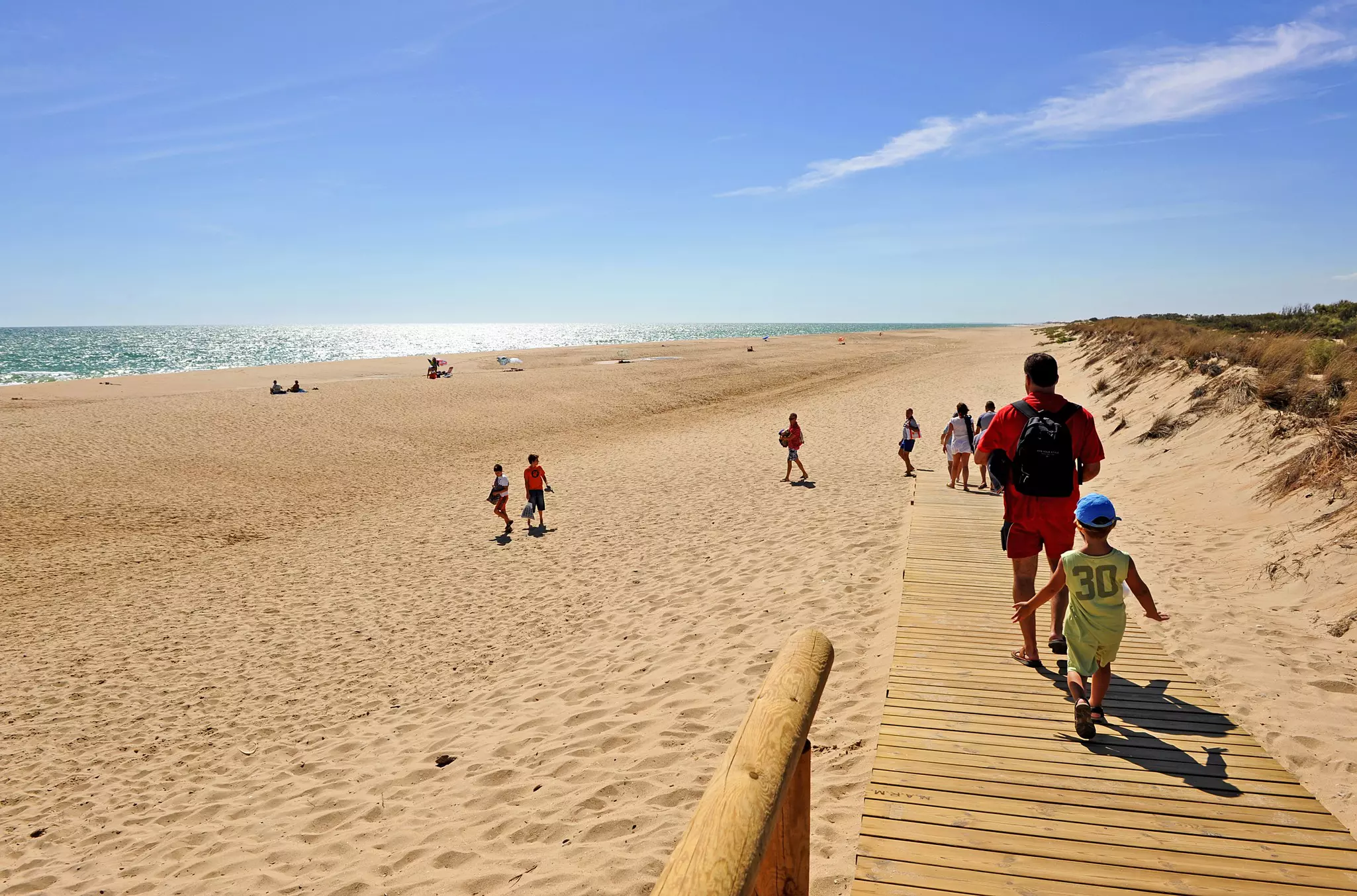 A family on the wooden walkway that leads down to a sandy beach called La Flecha del Rompido