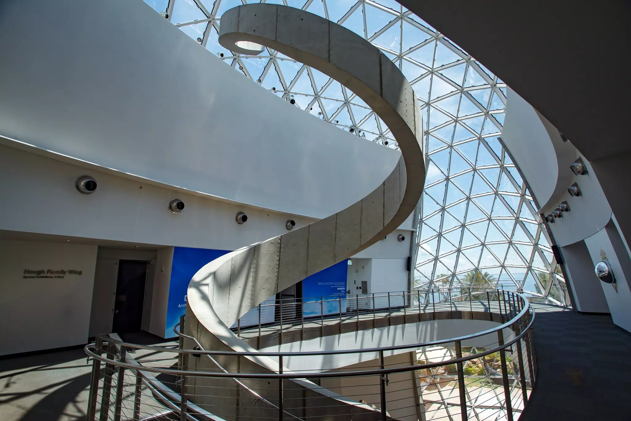 The top of a spiral staircase continues as a sculpture in the skylit atrium of a museum.