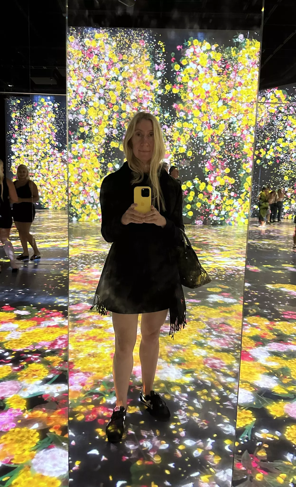 Caroline, the writer, takes a photo in an immersive exhibit where she is surrounded by images of flowers.