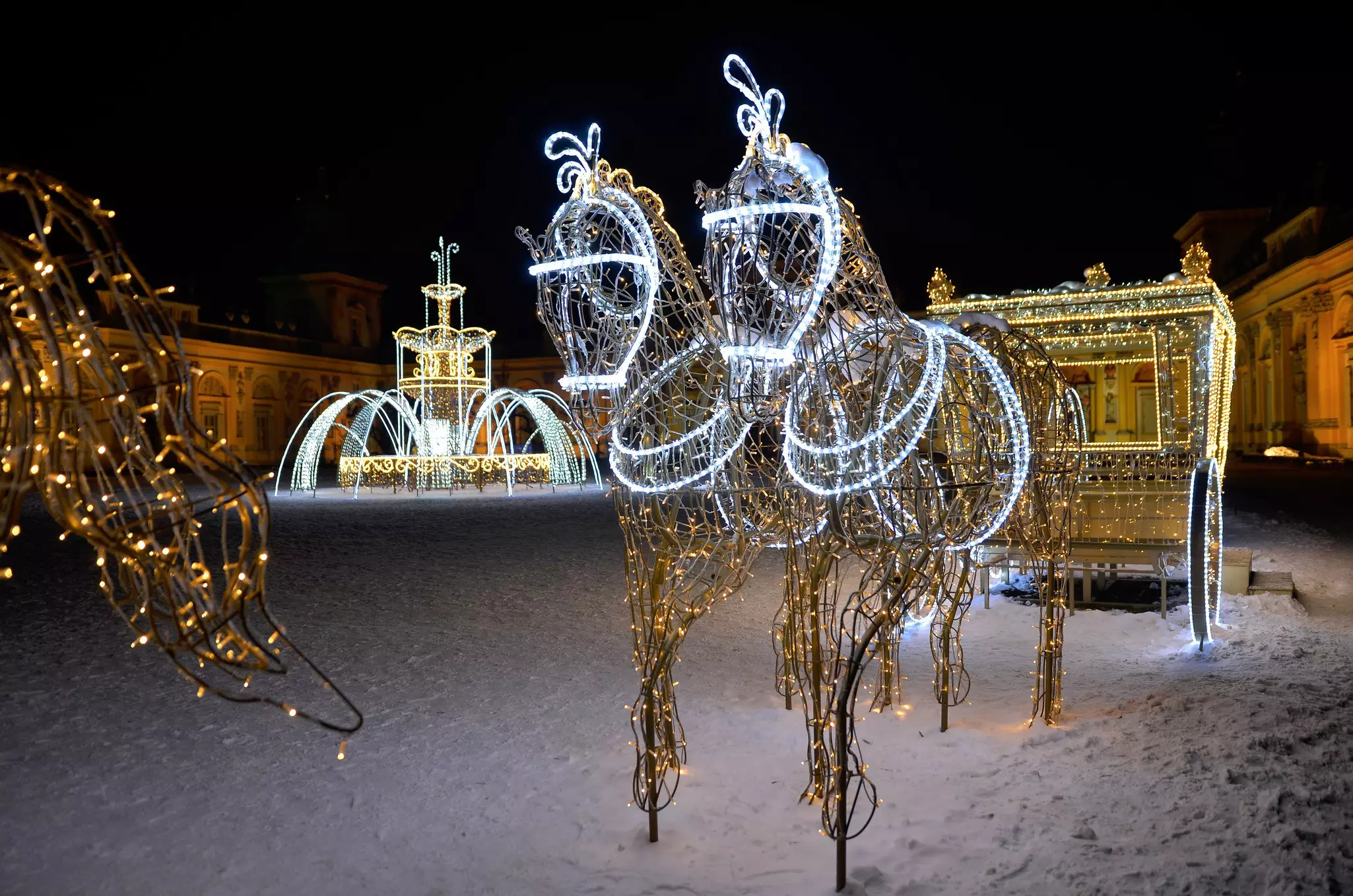 A horse and cart made of lights in the snow at night in a park in Warsaw, Poland.