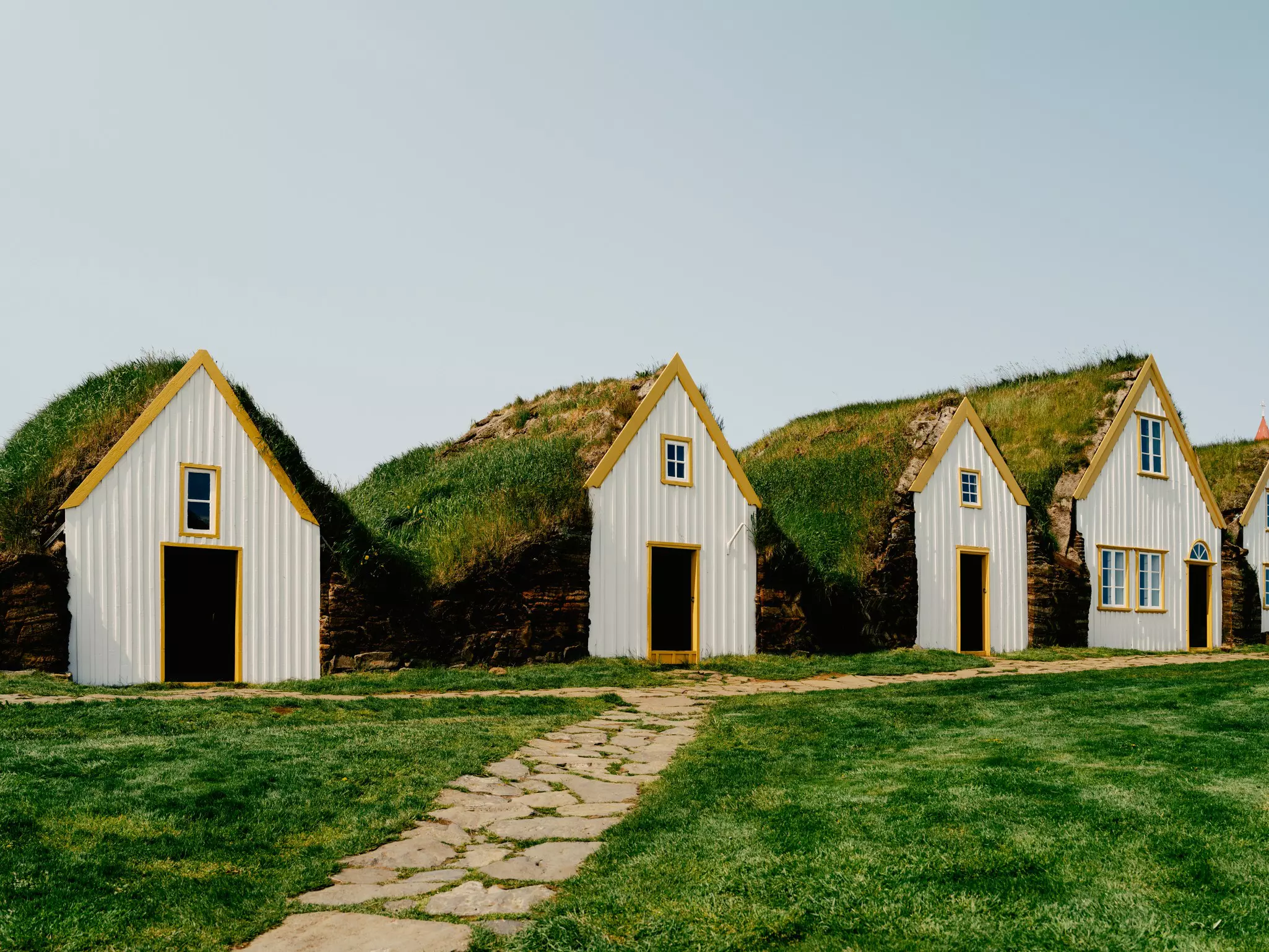 White houses with yellow trim and grass roofs.