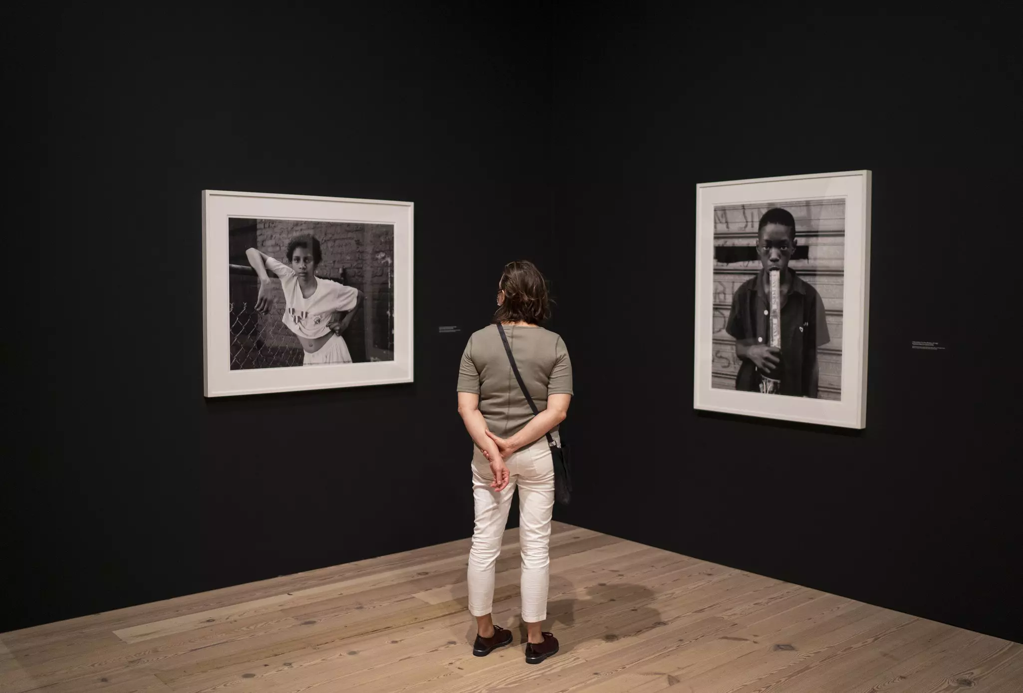 A museum visitor faces a corner of a room, between two large black-and-white framed photographs at the Whitney Museum of American Art