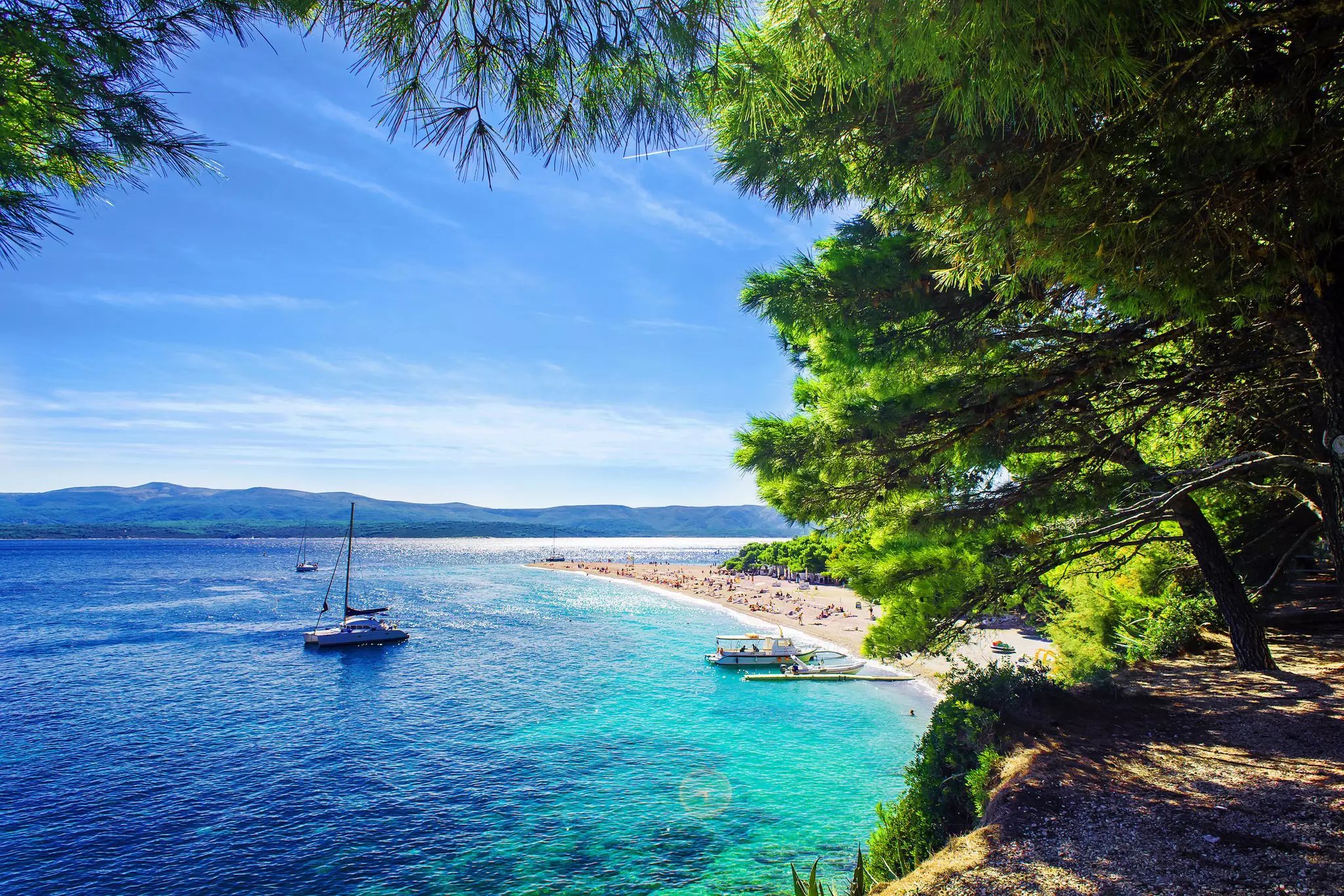 A sail boat off the shores of a sandy beach, Zlatni Rat in Brač, Croatia 