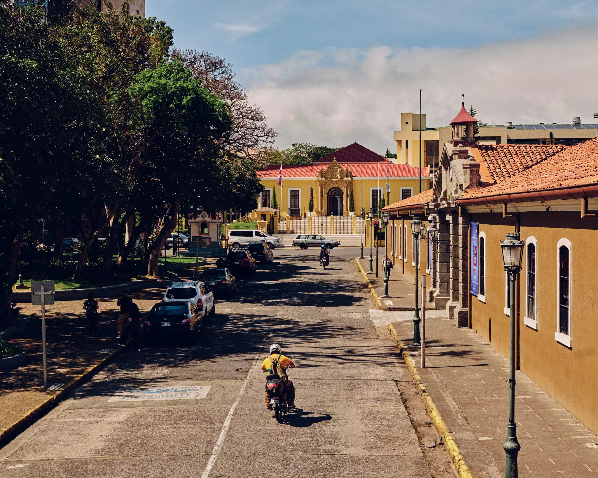Parked cars on a quiet residential street as a motorcycle passes by