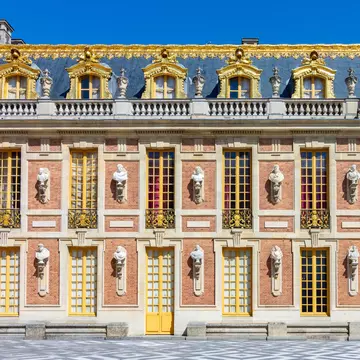 The façade of the Palace of Versailles featuring a combination of red brick, white stone and grey slate, highlighted by marble busts.