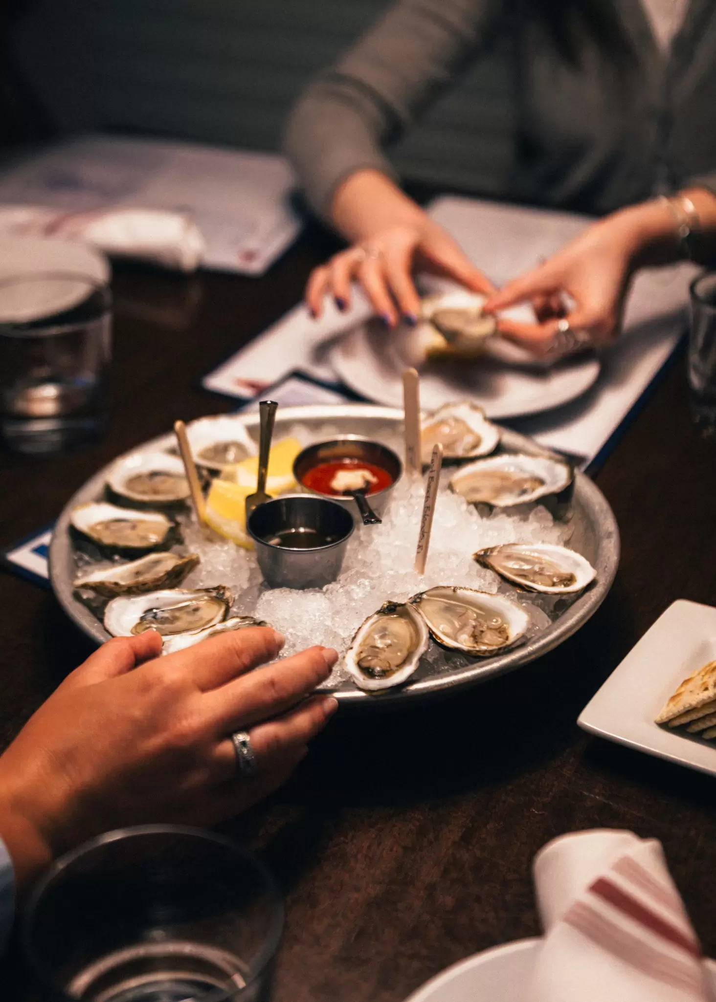 Hands of diners viewable as they dine on fresh oysters in Newport, Rhode Island.