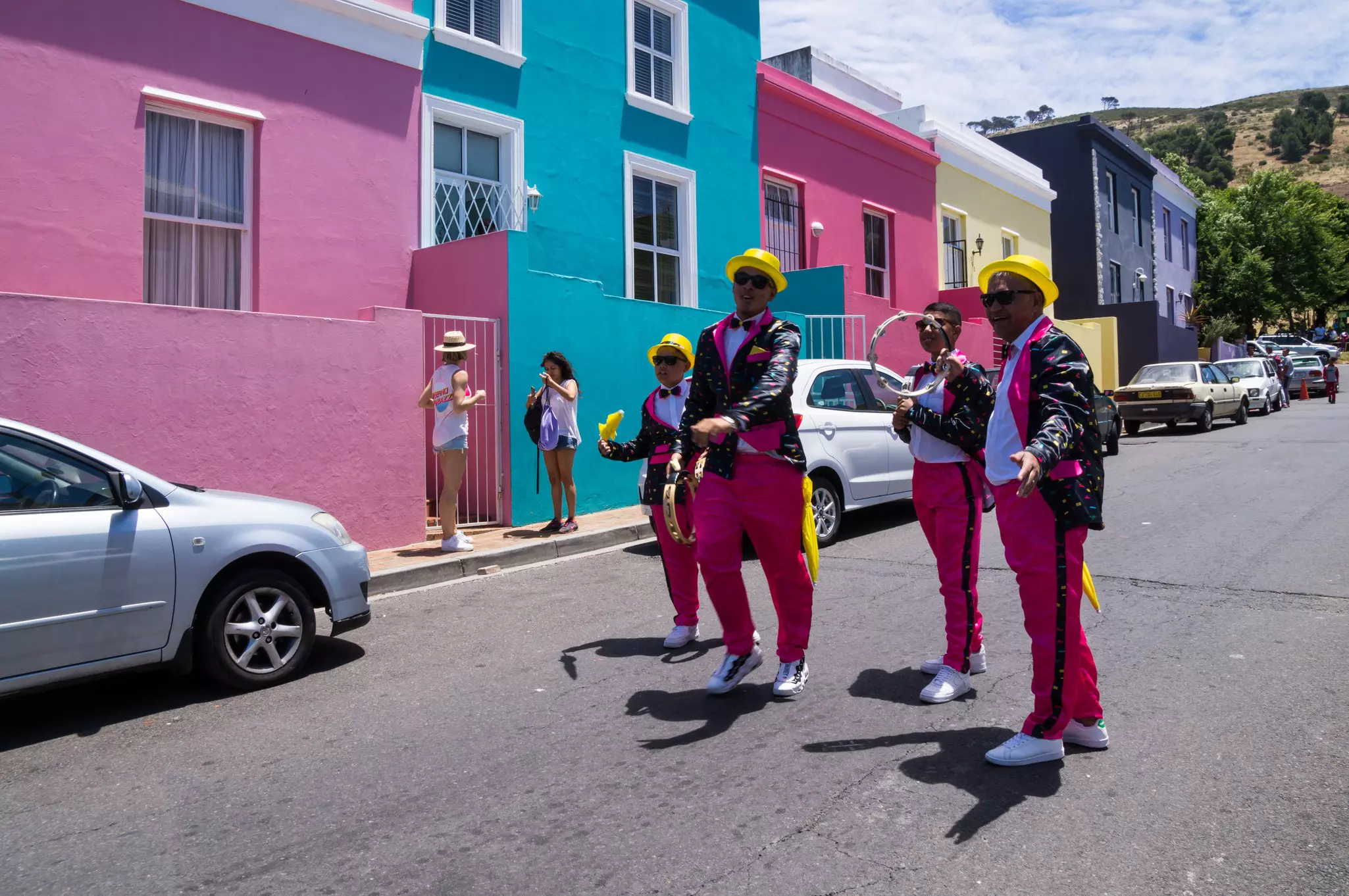 Men wearing splashy pink and black outfits with yellow hats at Kaapse Klopse, the Cape Town Minstrel Carnival