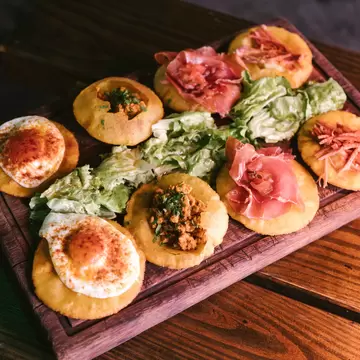 A wooden board of tortos (corn fritters), a popular tapas dish in Asturias, Spain. 