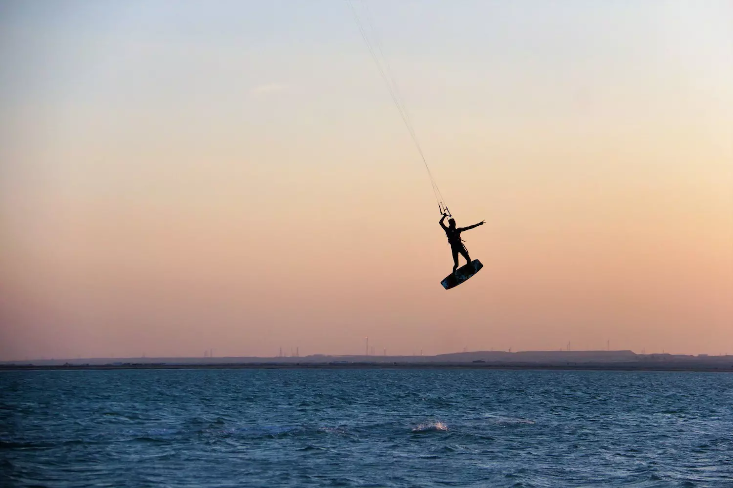 A person kitesurfs at sunset off a beach in Qatar, Arabian Peninsula, Middle East