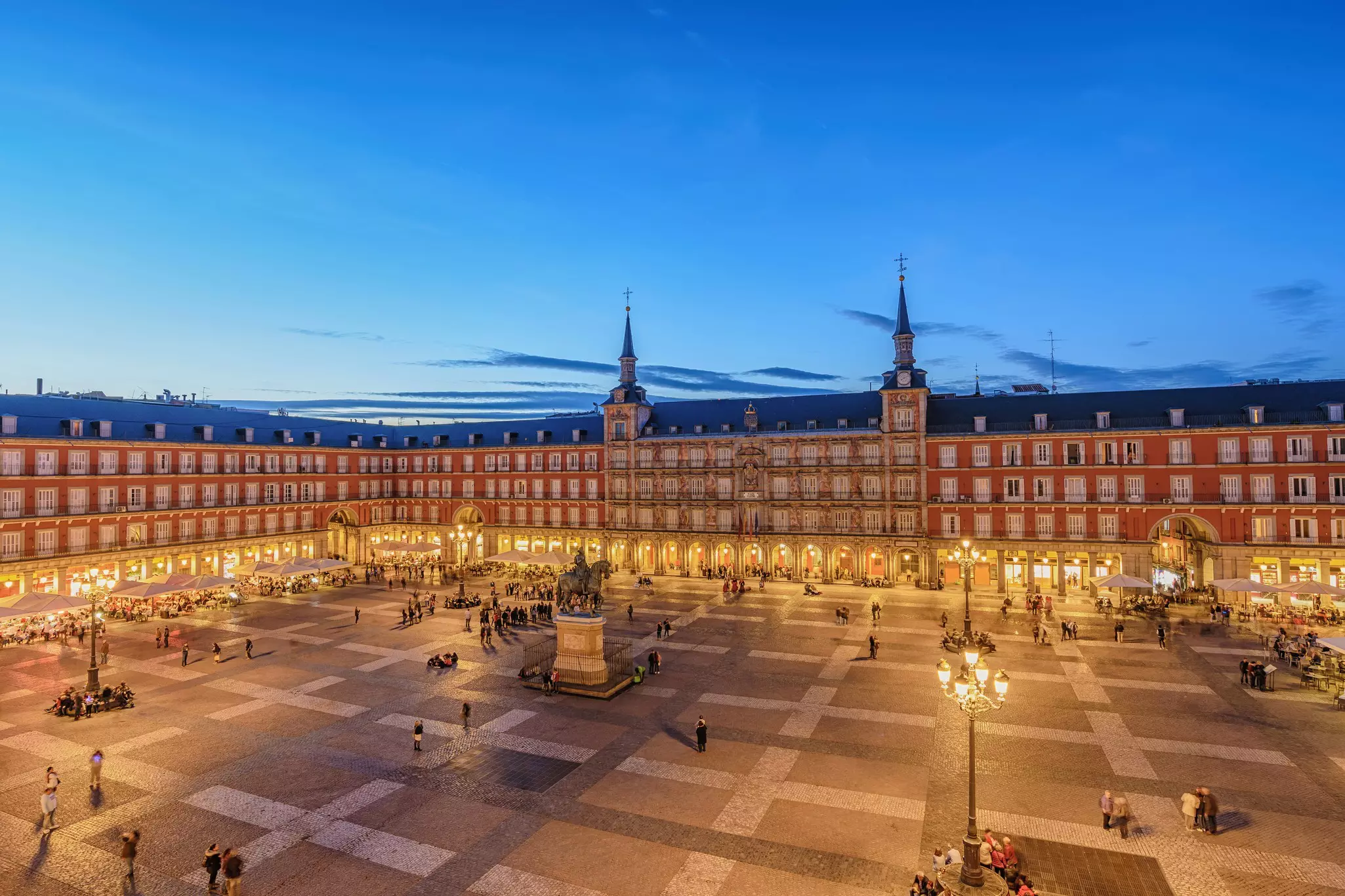 A large city square lit up at night with people milling around