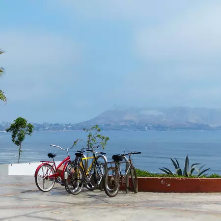 Bicycles lean against a wall by a path above the sea in Lima, Peru.