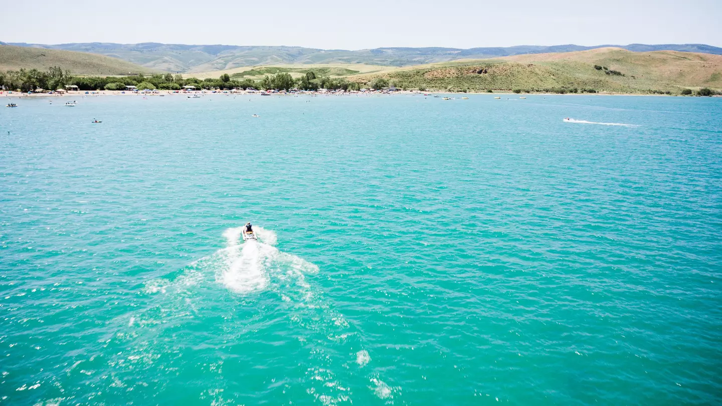 An aerial shot of a boat crossing the blue waters of Bear Lake at the Utah-Idaho border