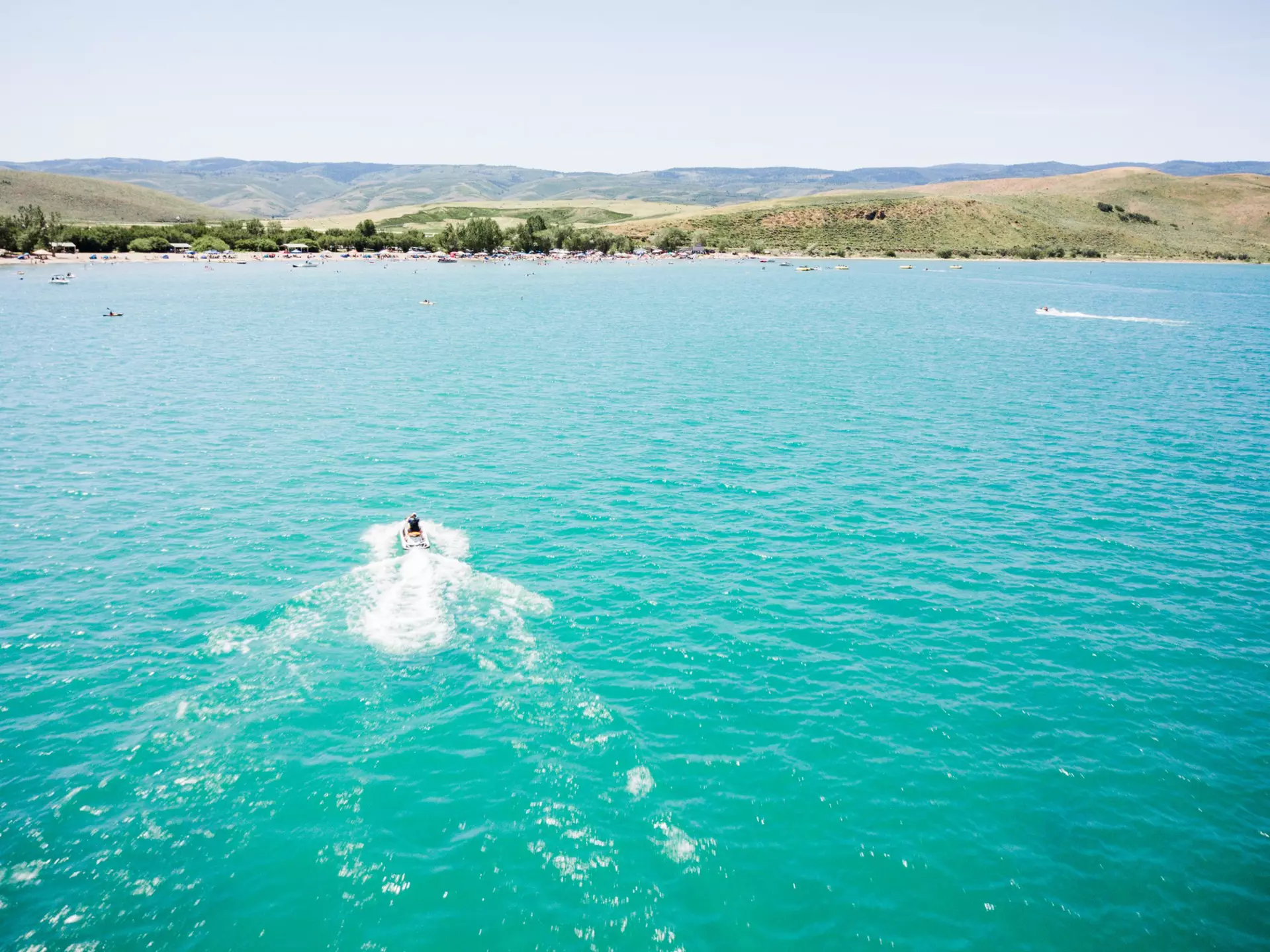 An aerial shot of a boat crossing the blue waters of Bear Lake at the Utah-Idaho border