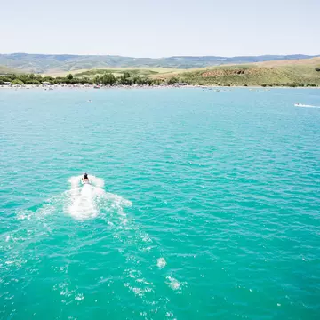 An aerial shot of a boat crossing the blue waters of Bear Lake at the Utah-Idaho border