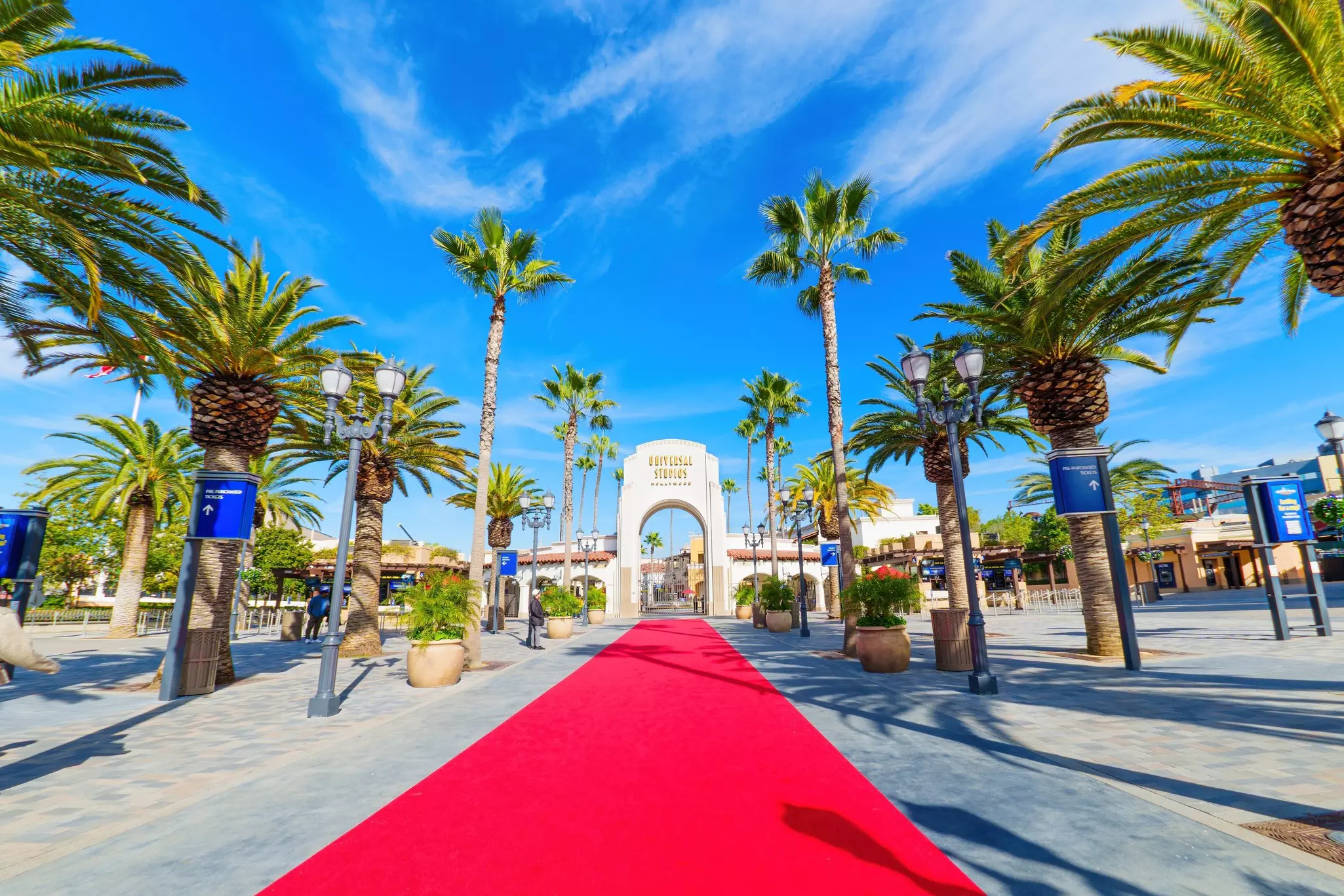 Universal Studios Hollywood entrance with red carpet and palm trees on a sunny day