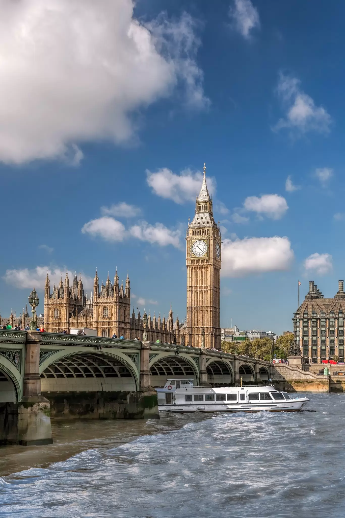 View of a tourboat on the River Thames with Big Ben in the background in London, UK.
