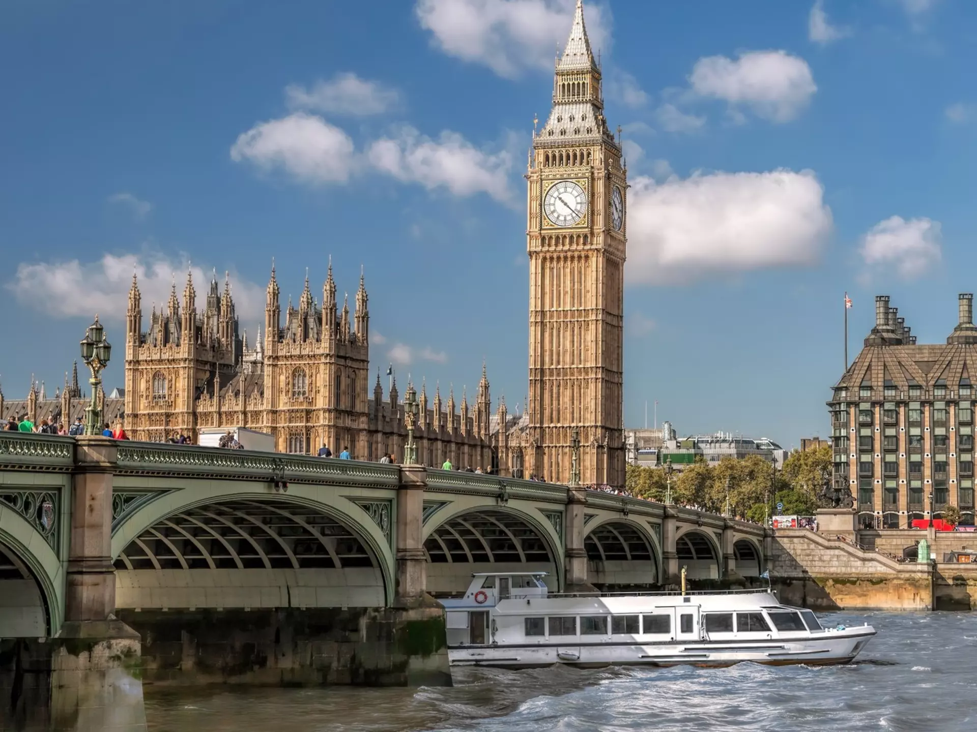 View of a tourboat on the River Thames with Big Ben in the background in London, UK.