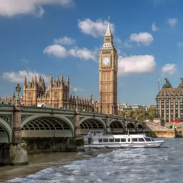 View of a tourboat on the River Thames with Big Ben in the background in London, UK.