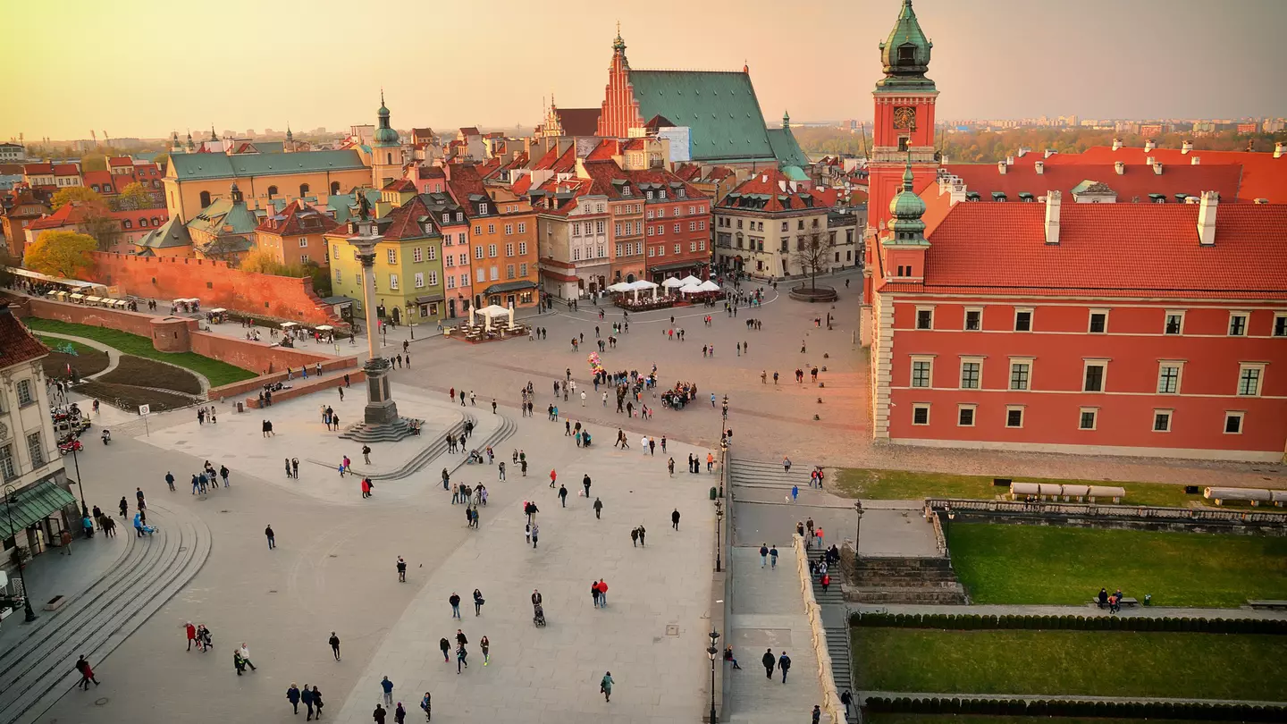 Elevated view of town square, Warsaw. Many people walking through a courtyard during the late afternoon.