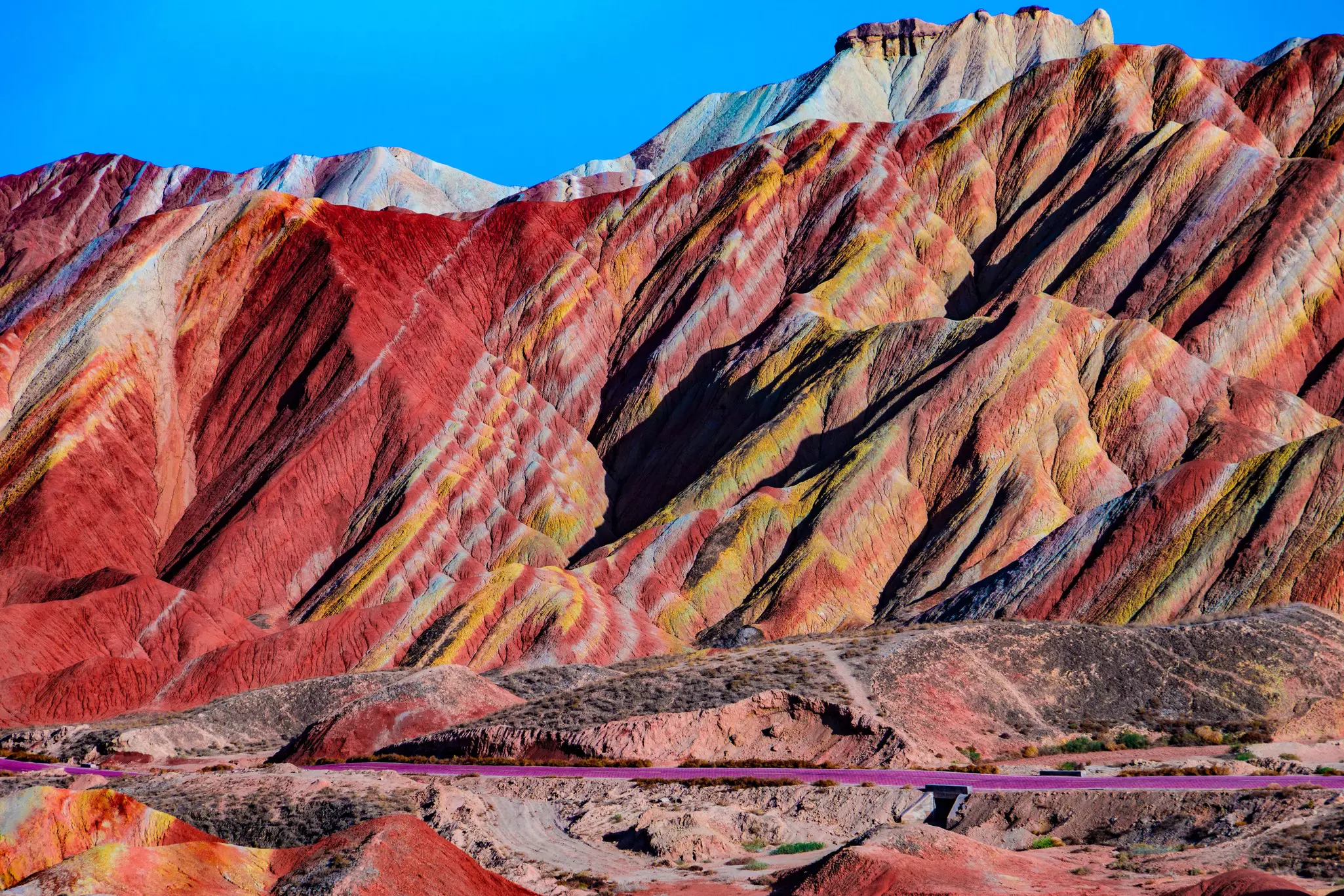 A mountain is streaked with bright, naturally occurring colors, including red, yellow and orange.