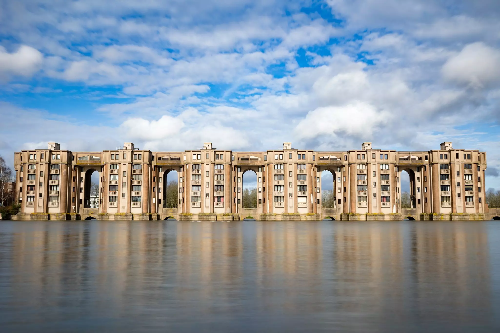 Buildings by a lake, linked at the top by walkways.