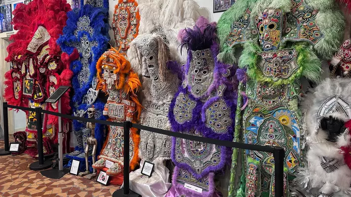 Elaborate and colorful costumes with beading and feathers exhibited at a museum.
