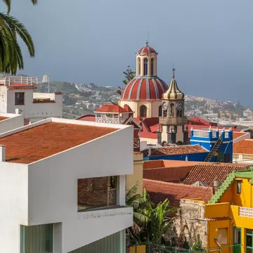 A town with colorful buildings surrounding a terracotta-domed church.