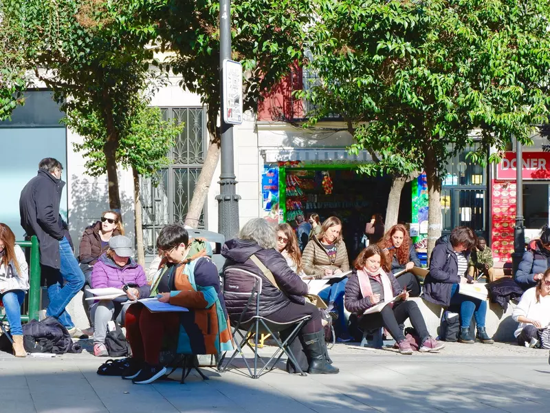 Group of people of different ages painting together outside in the local park