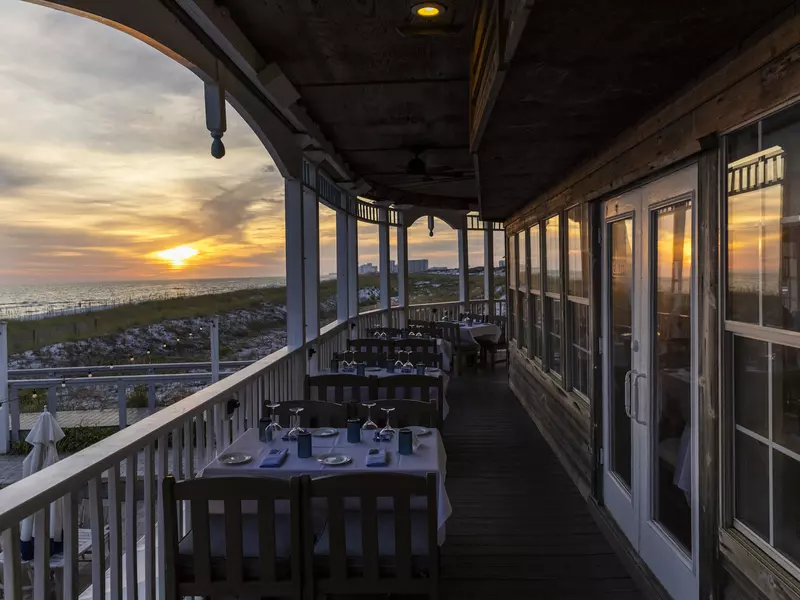 Outdoor tables at Beachwalk Cafe, with the sunset over the beach in the background.