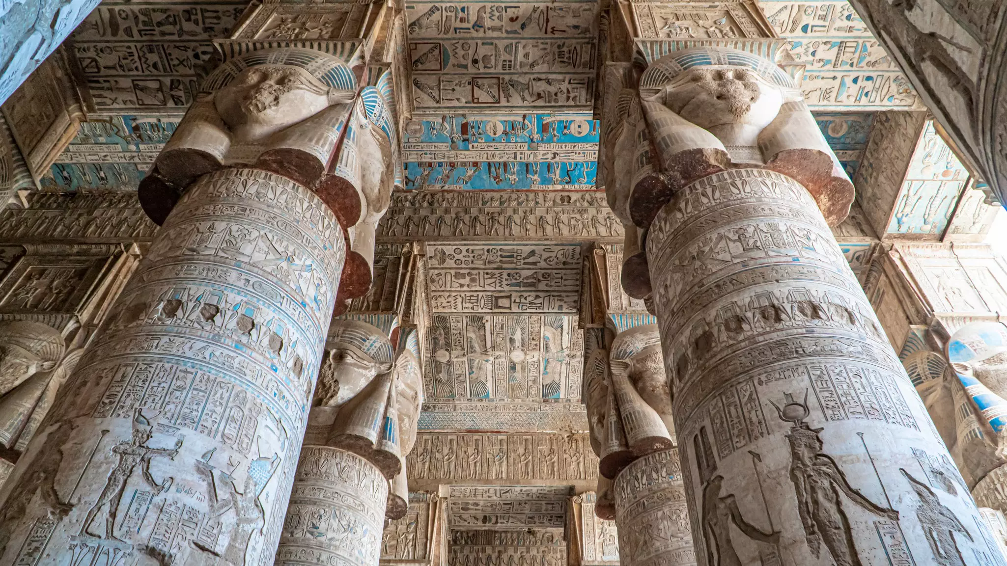 A vast chamber with floor-to-ceiling columns and a ceiling covered in carvings and hieroglyphs.