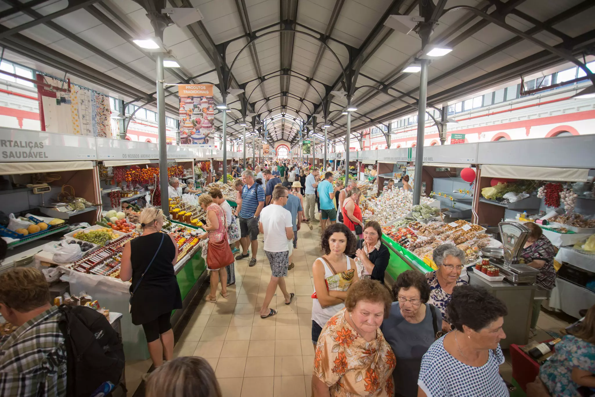 People milling around a market aisle lined with food