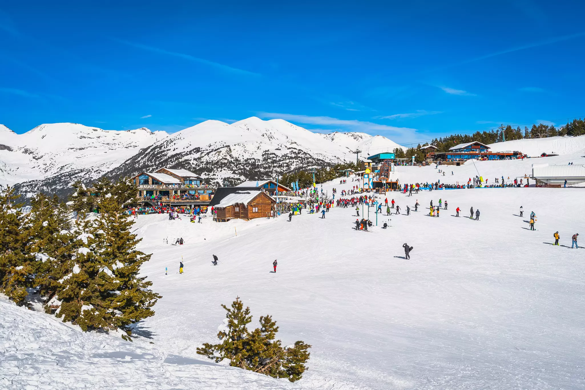 A ski area with snow-capped mountains and people skiing